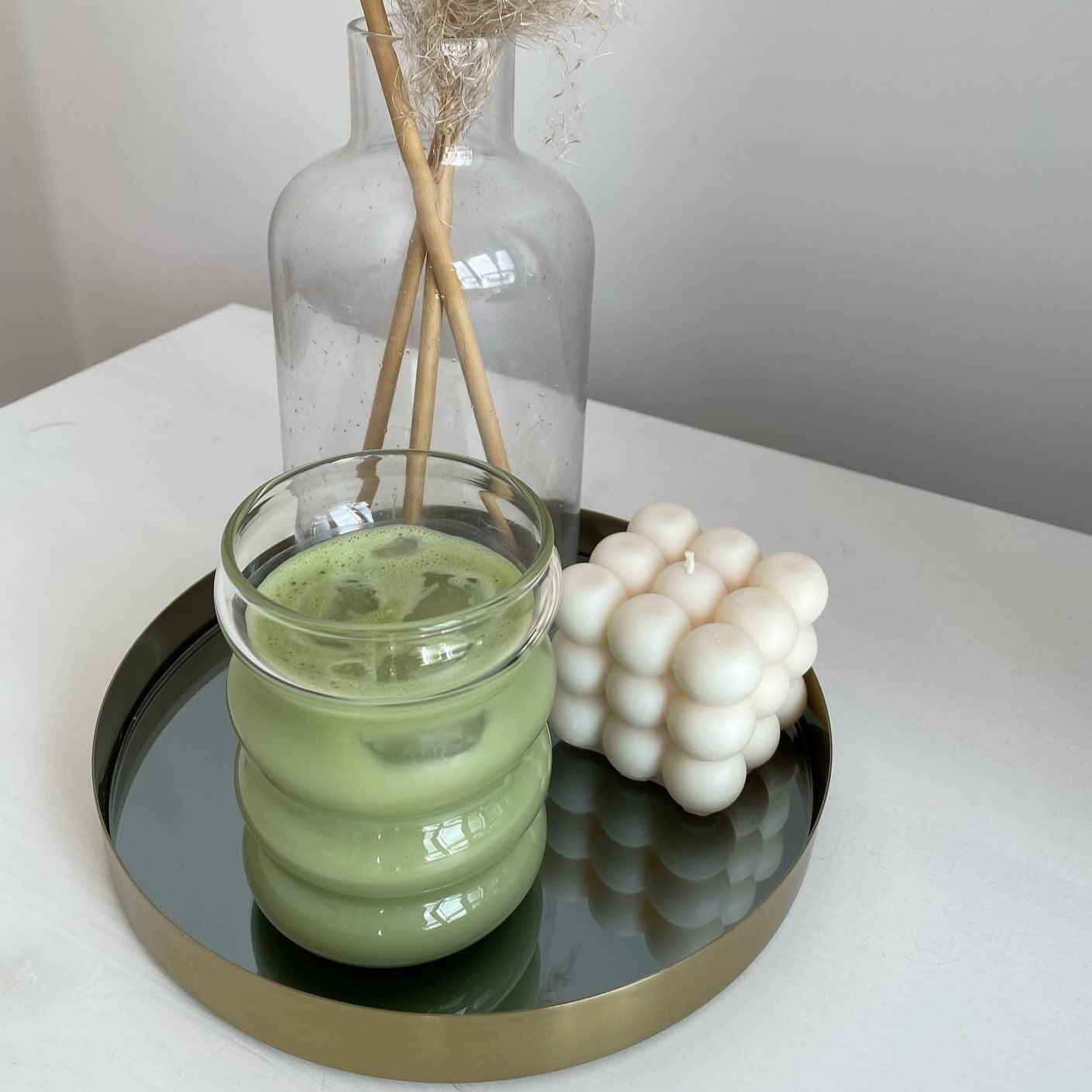 Hier sieht man unser Venice dream Bubble Glas. In dem Glas ist Matcha Latte enthalten. Das elegante und ästhetische Bubble Glas ist stilvoll auf einem Tablet. Es hat ein gewölbtes Design und sieht minimalistisch aus. Das Bubble Glas ist purer Luxus.