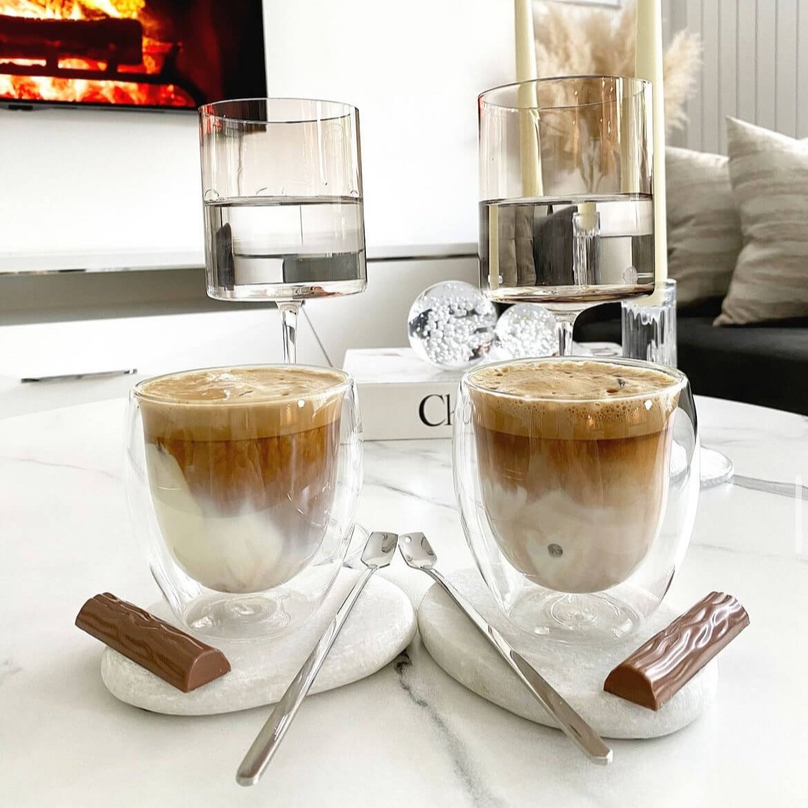 Zwei Double Wall Gläser, 250ml, gefüllt mit Cappuccino, daneben ein Duplo. Hochwertige, stilvolle Trinkgefäße mit doppelwandigem Design für heiße und kalte Getränke wie Kaffee, Cappuccino, Eiskaffee und Cocktails. Diese modernen, ästhetischen Gläser bieten ein luxuriöses Trinkgefühl und sind perfekt für eine elegante und trendige Tischdekoration. Ideal für stilvolle Momente und luxuriösen Genuss.